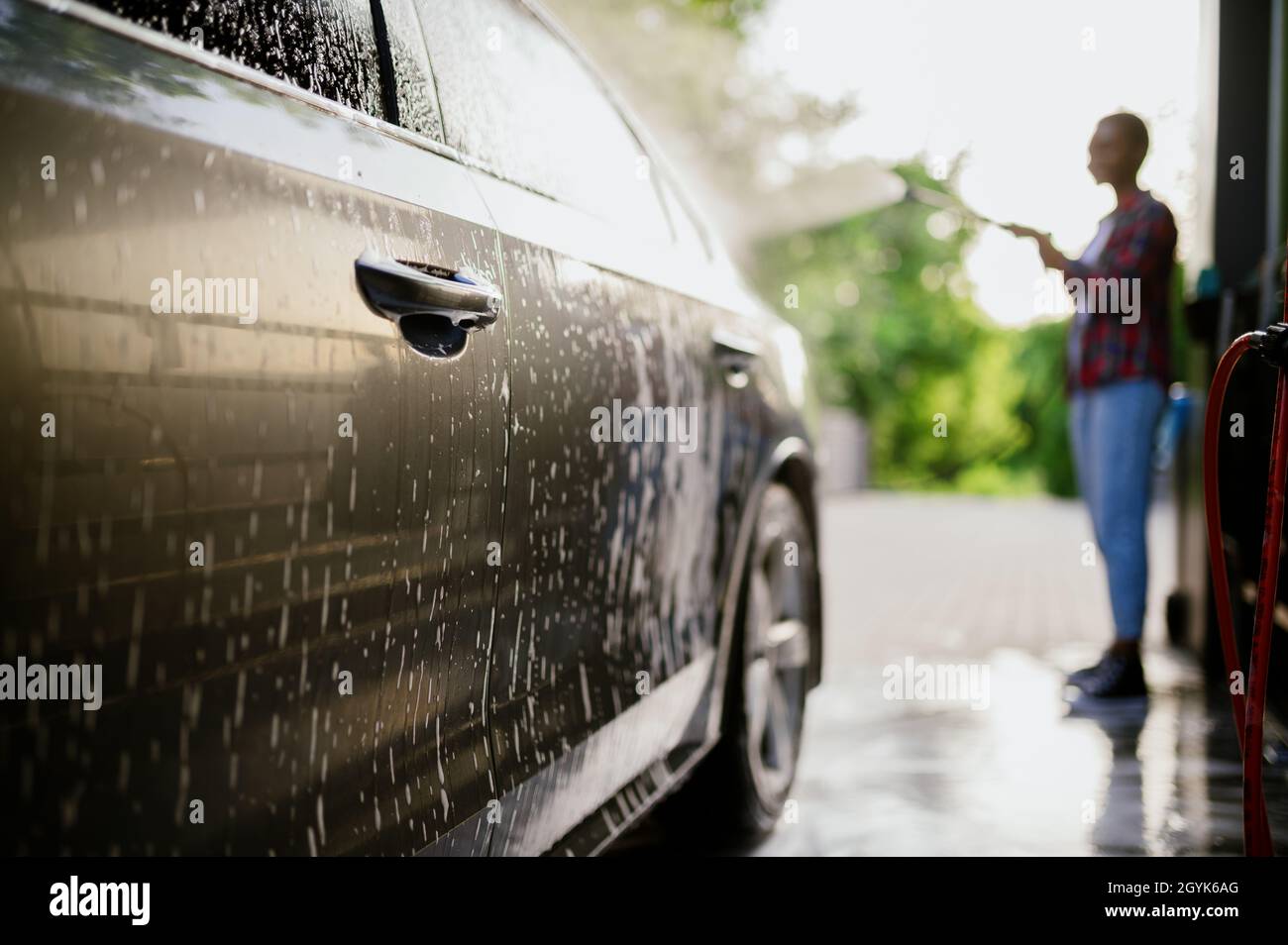 Donna washes via schiuma dalla macchina, mano auto lavaggio Foto Stock
