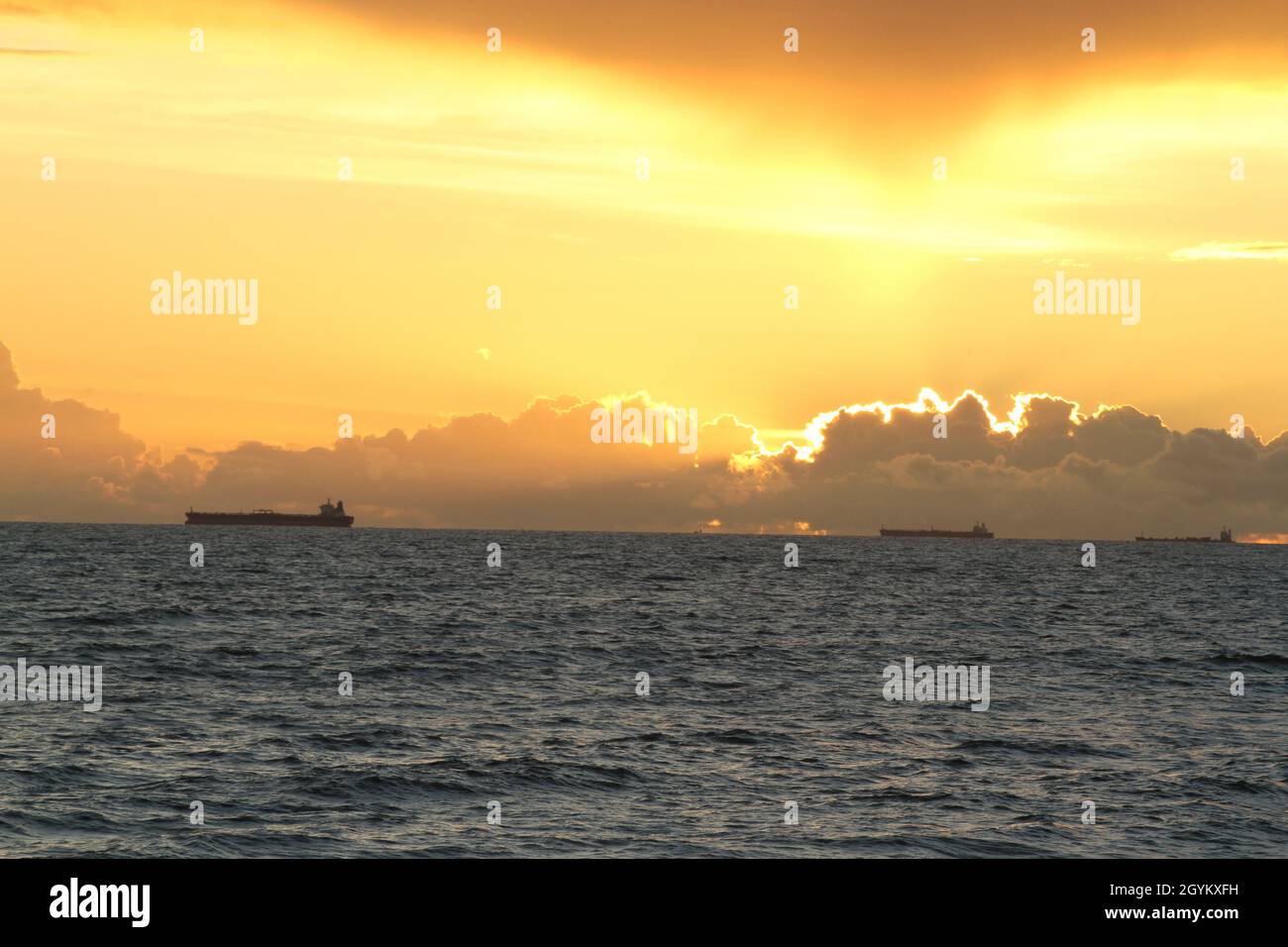 le navi all'orizzonte sono in corso durante il tramonto dorato, vista dal mare Foto Stock