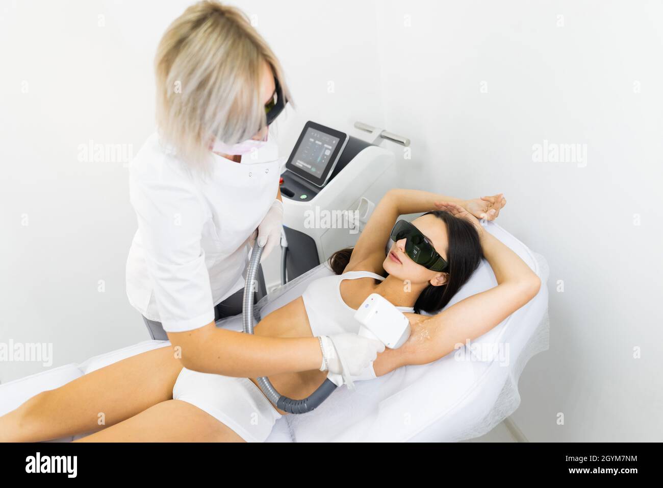Estetista rimuove i capelli delle ascelle di una donna con un laser Foto Stock