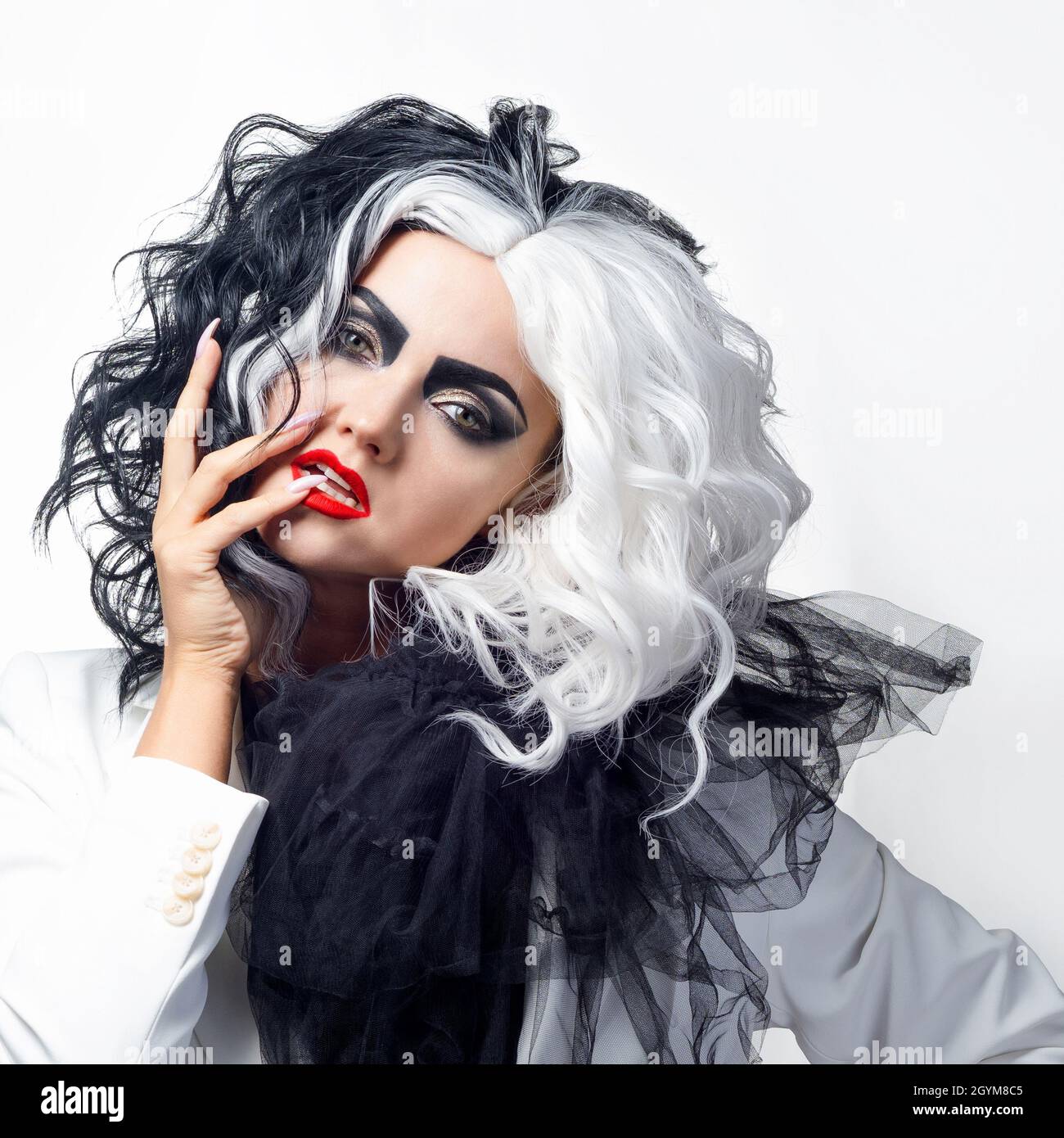 Una donna carismatica insolita in un abito bianco e nero con capelli bianchi e neri, un'immagine audace ed elegante di un criminale per Halloween Foto Stock