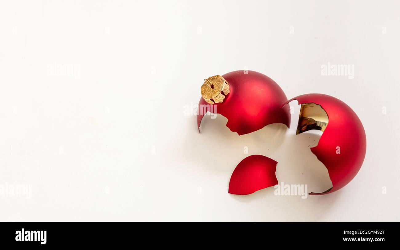 Natale bauble rotto isolato su sfondo bianco, vista closeup. La palla rossa di Natale si è schiantata a pezzi. Incidente di vacanza, fragilità, rabbia concetto Foto Stock