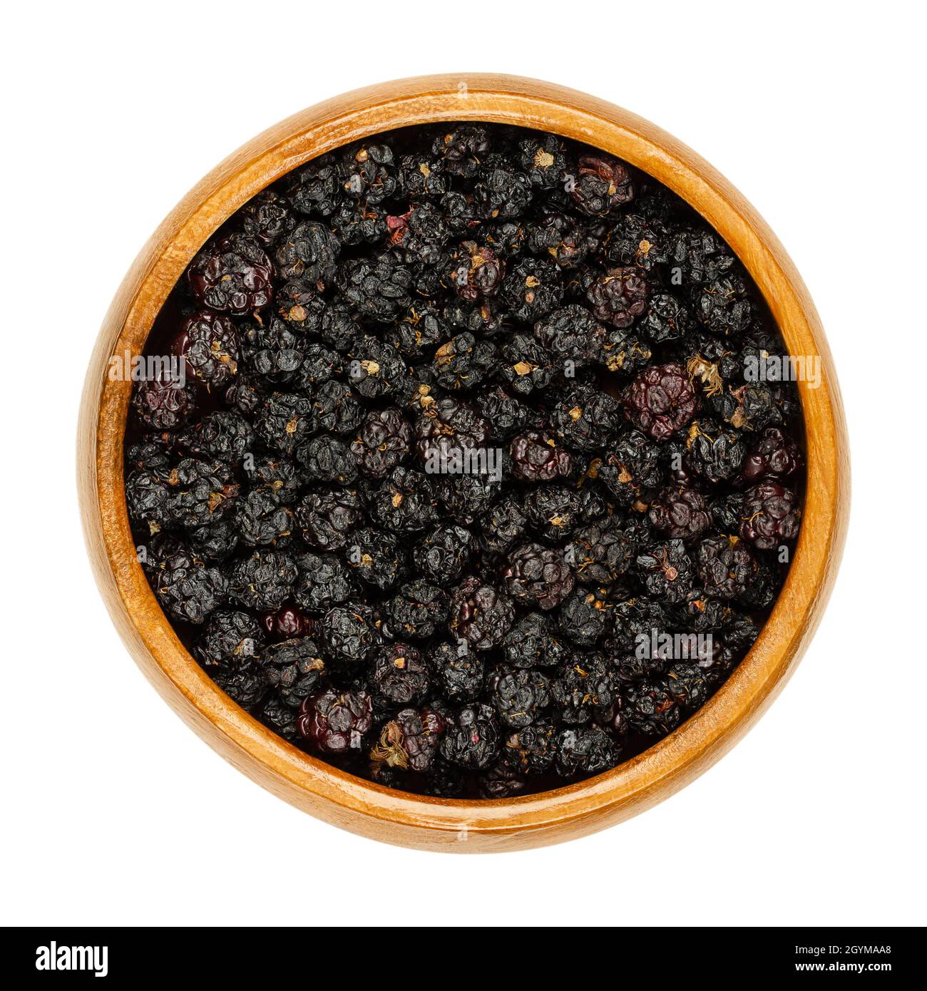 Bacche nere europee secche mature in una ciotola di legno. Brambles selvaggi essiccati all'aria, Rubus fruticosus, un frutto dolce, usato per l'additivo del tè. Foto Stock
