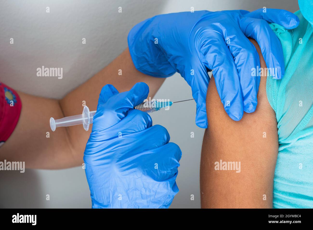 l'infermiera dei bambini inietta il braccio della bambina marrone. le mani del medico con i guanti di gomma che iniettano il covid-19 o il vaccino di flu. concetto medico, salute e. Foto Stock