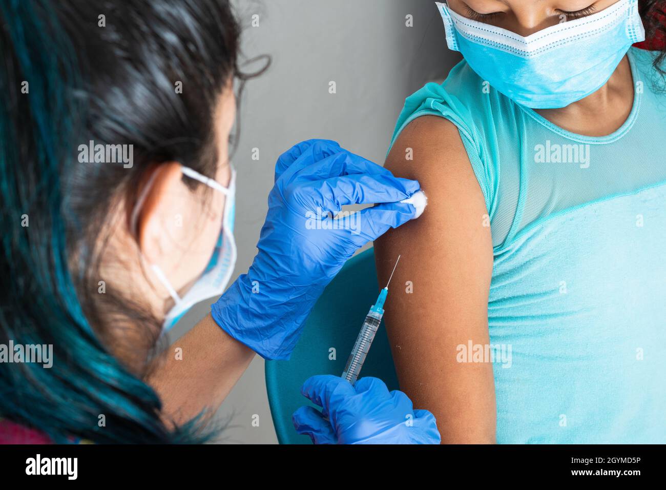 infermiera per bambini disinfezione del braccio di una ragazza marrone prima di somministrare l'iniezione. medico che inietta il vaccino covid-19. vaccino influenzale. concetto medico, salute Foto Stock