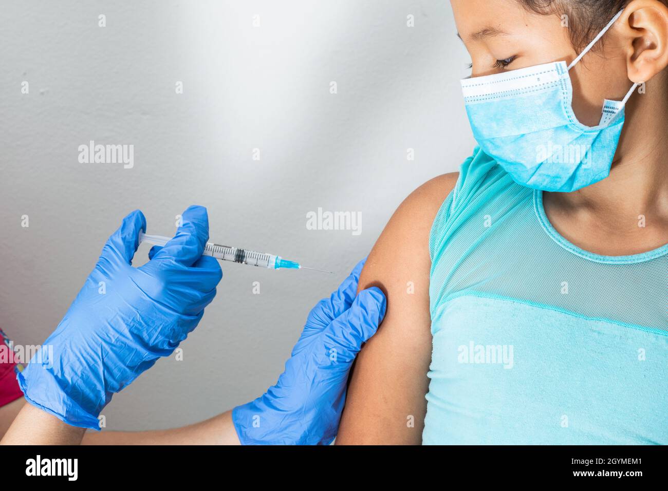 l'infermiera dei bambini che inietta il braccio della ragazza marrone. la mano del medico con i guanti di gomma che inietta il vaccino di covid-19. il vaccino di flu. il concetto medico, la salute e la padella Foto Stock
