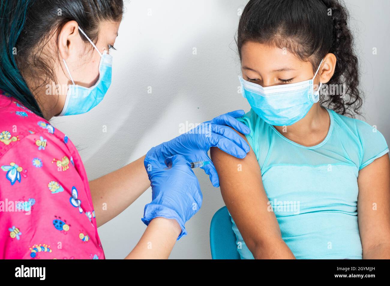 infermiera per bambini che inietta il braccio di una ragazza marrone. (bambina di 8 anni), le mani del medico con guanti di gomma iniettando vaccino covid-19. vaccino influenzale Foto Stock