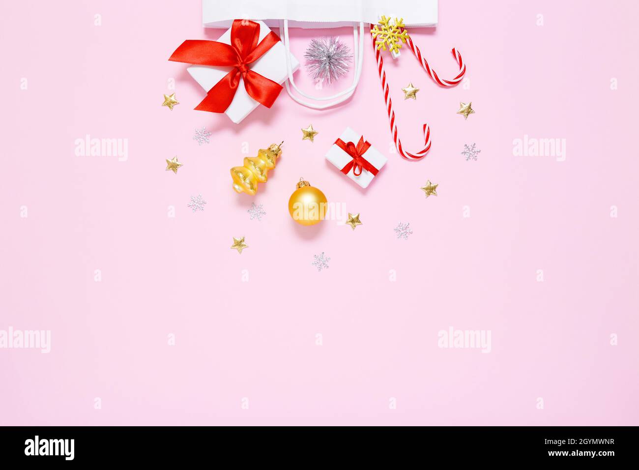 Natale, composizione di Capodanno. Borsa di carta bianca con regali, caramelle dolci, decorazioni per le vacanze, palle d'oro, stelle con glitter a base di pastello p Foto Stock