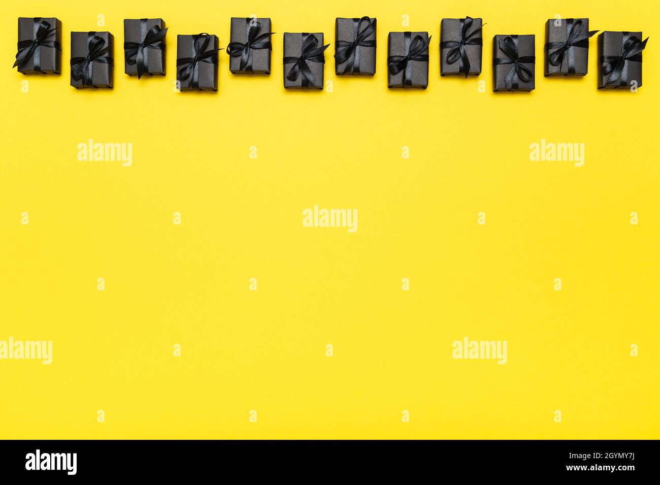 Scatole regalo nere con nastri neri su sfondo giallo brillante e ricco. Black Friday vendita piatto, vista dall'alto, spazio copia Foto Stock