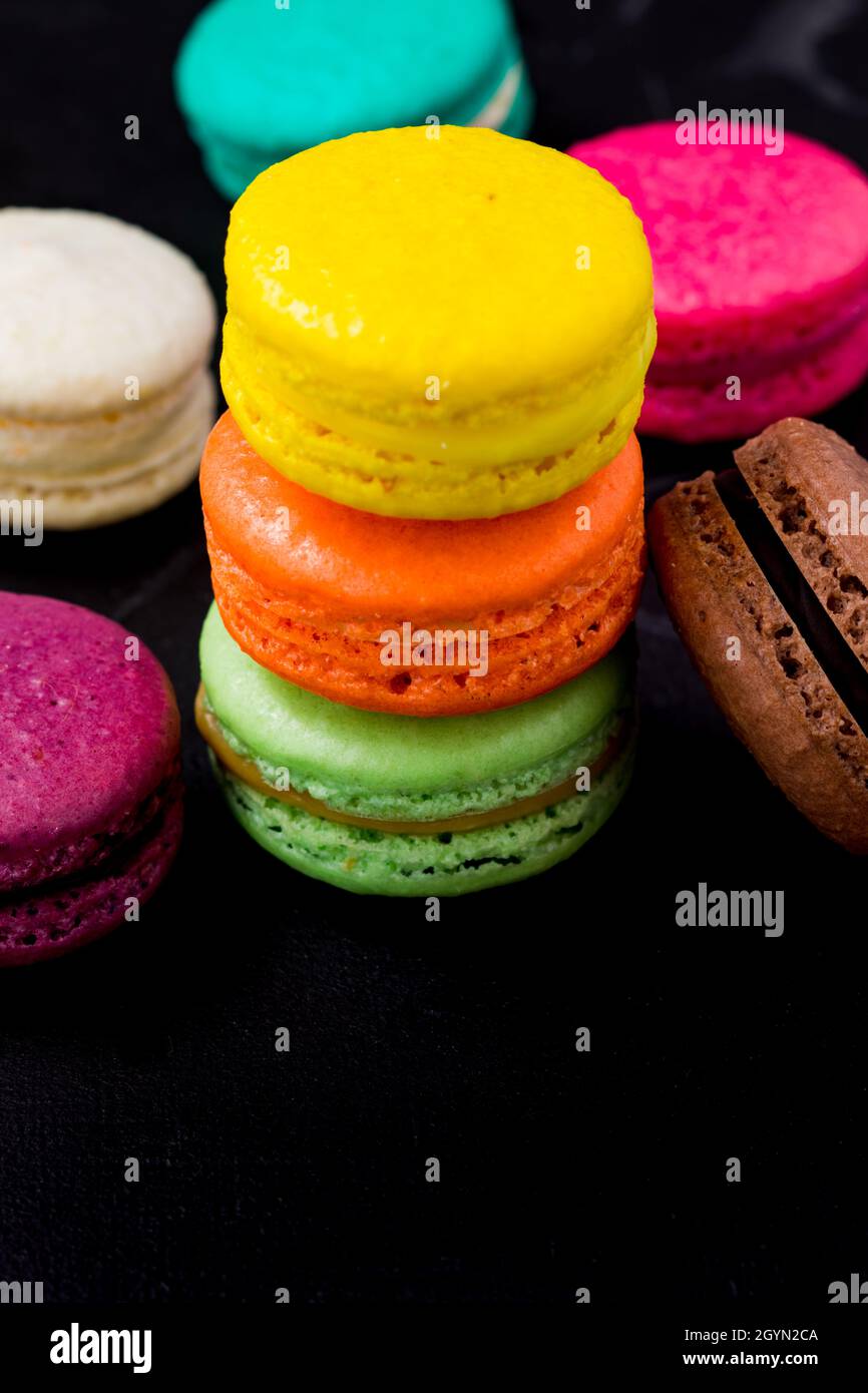 Biscotti macaron colorati su sfondo nero Foto Stock
