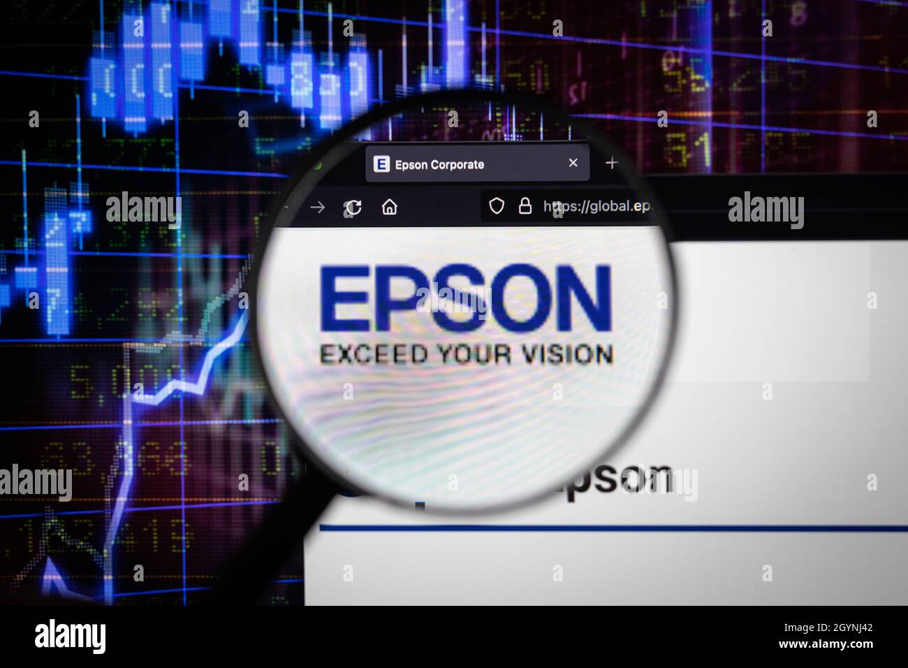 Epson, logo aziendale su un sito web con blurry sviluppi del mercato azionario in background, visto su uno schermo del computer attraverso una lente d'ingrandimento Foto Stock