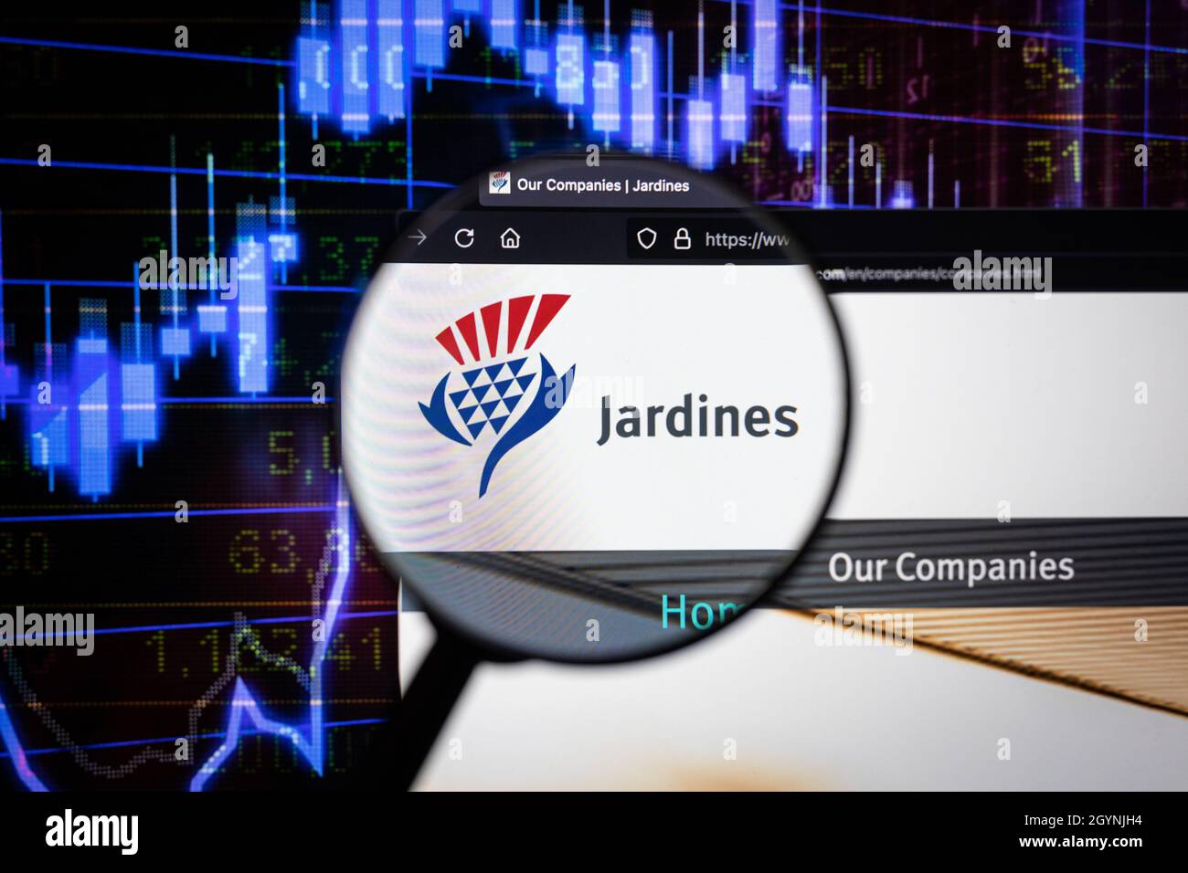Jardines Company logo su un sito web con blurry mercato azionario sviluppi in background, visto su uno schermo di computer attraverso una lente d'ingrandimento Foto Stock