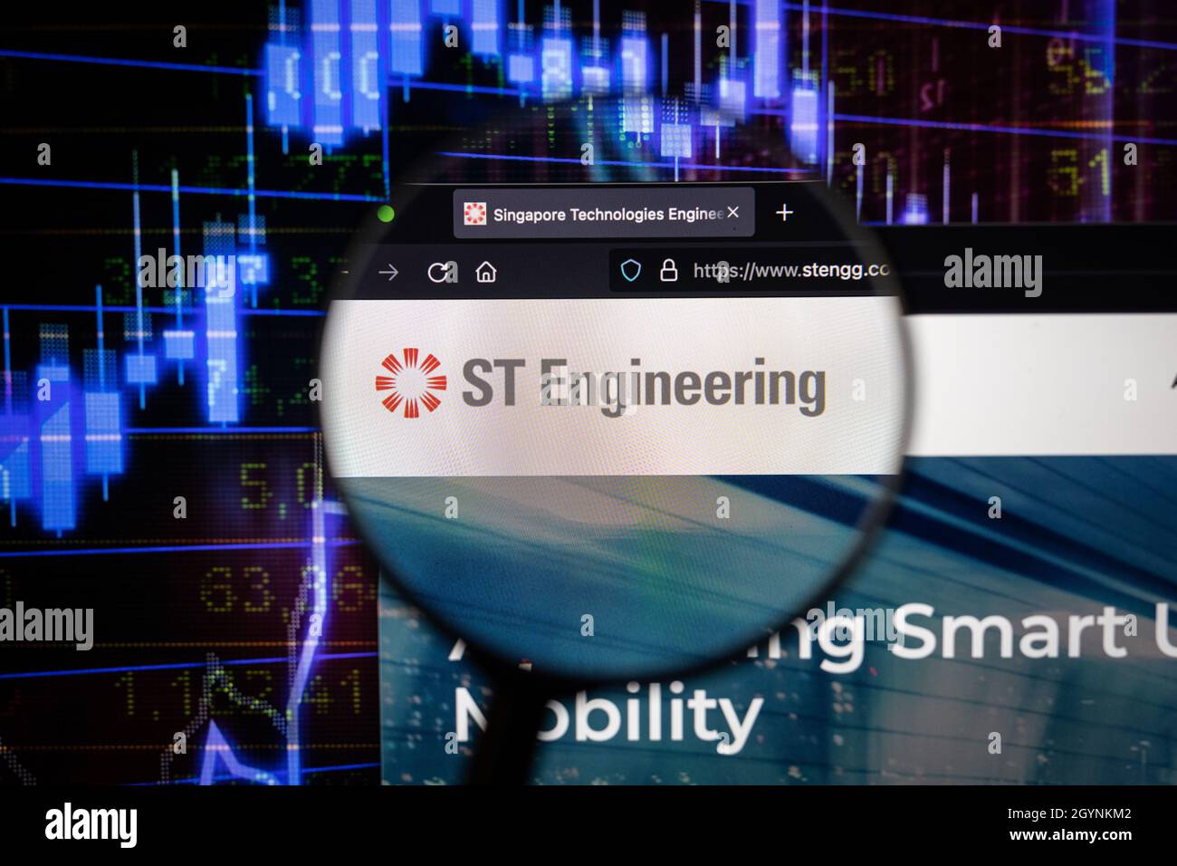 LOGO DELLA SOCIETÀ DI ingegneria ST su un sito web con sviluppi del mercato azionario sfocati in background, visto su uno schermo del computer attraverso una lente d'ingrandimento Foto Stock