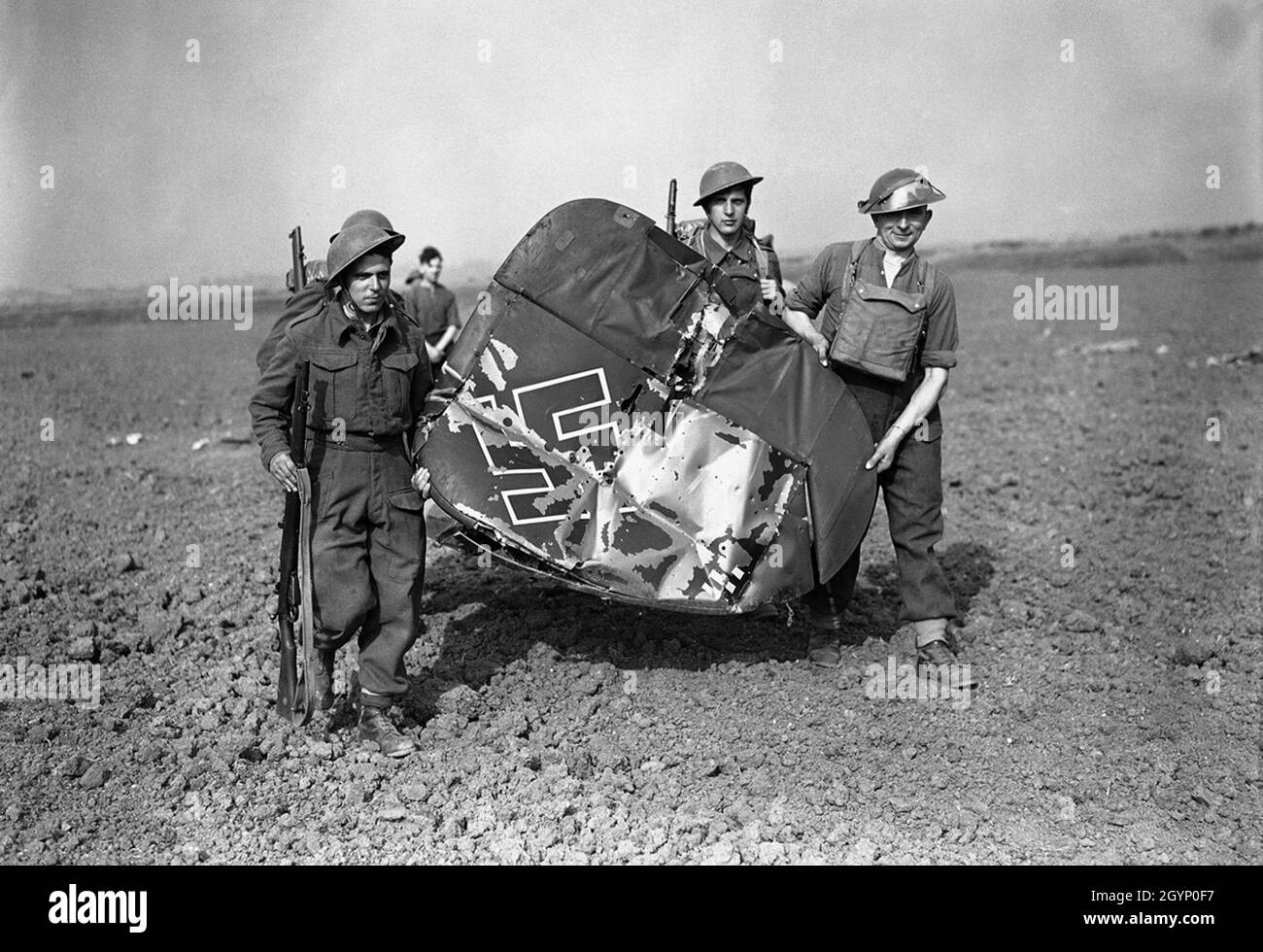 Soldati che trasportano un pezzo della coda di un combattente Messerschmitt Me-110 abbattutosi Foto Stock