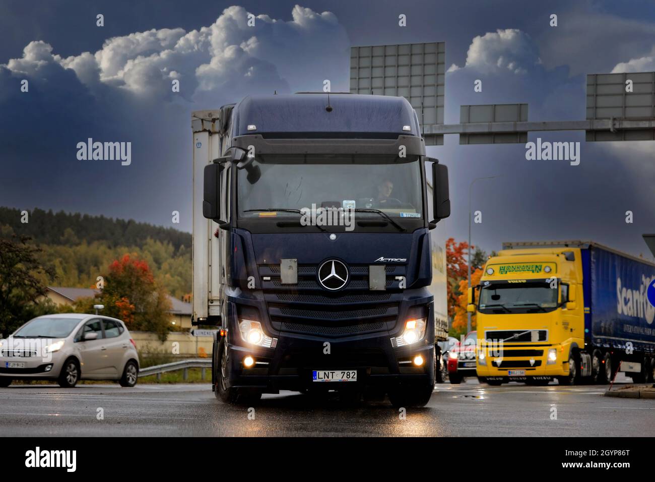 Incrocio stradale con Mercedes-Benz Actros nero trasporto camion svolta. Tempo piovoso, nuvole scure. Salo, Finlandia. Settembre 24, 2021. Foto Stock
