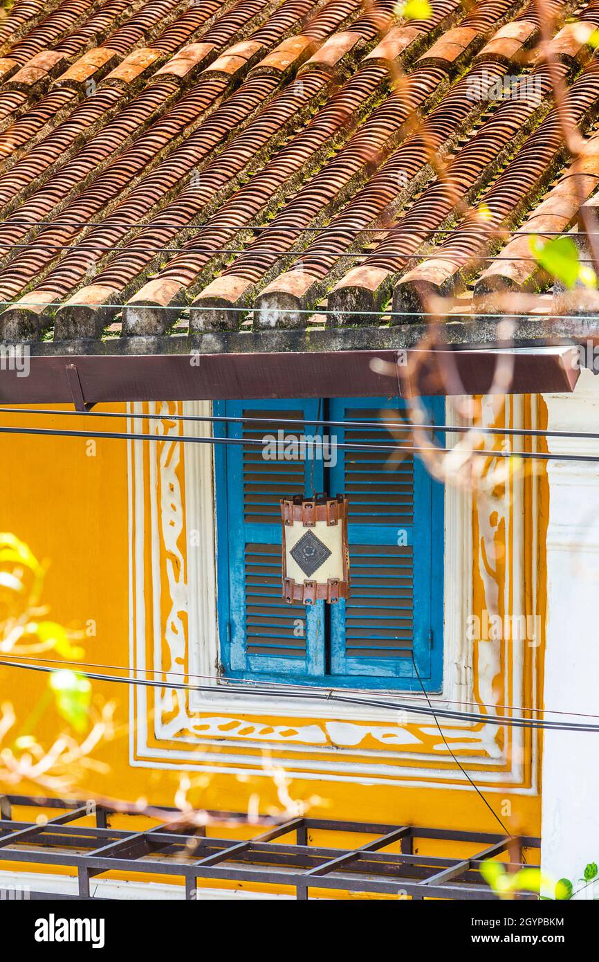 Hoi An architettura con edificio giallo, persiane turchesi finestre, design di vernice bianca e caratteristico tetto di tegole. Foto Stock