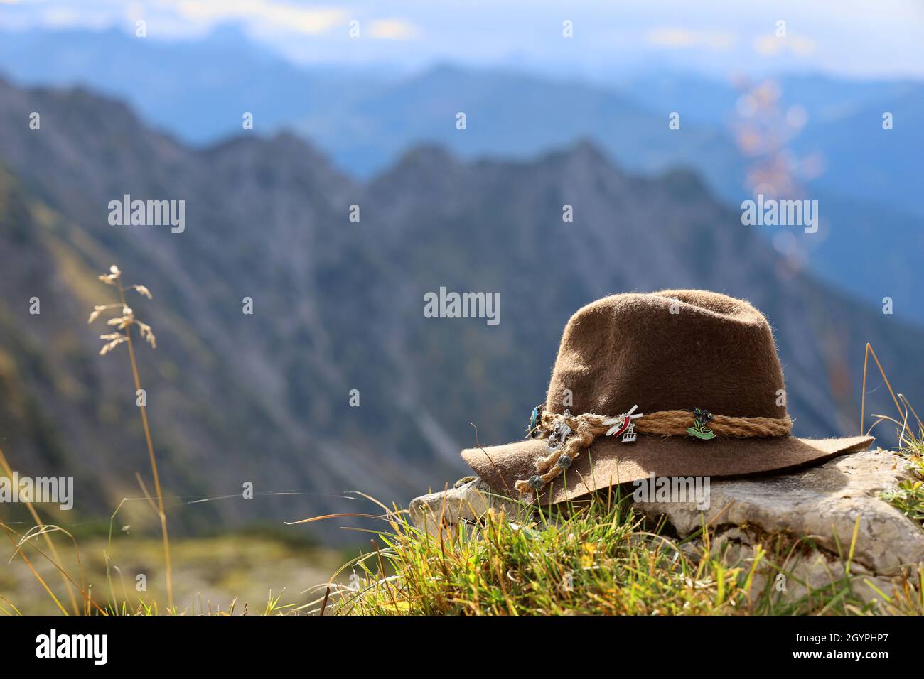 Cappello bavarese in feltro si trova sulle montagne di fronte ad un grandioso panorama montano delle Alpi, concetto di wanderlust Foto Stock