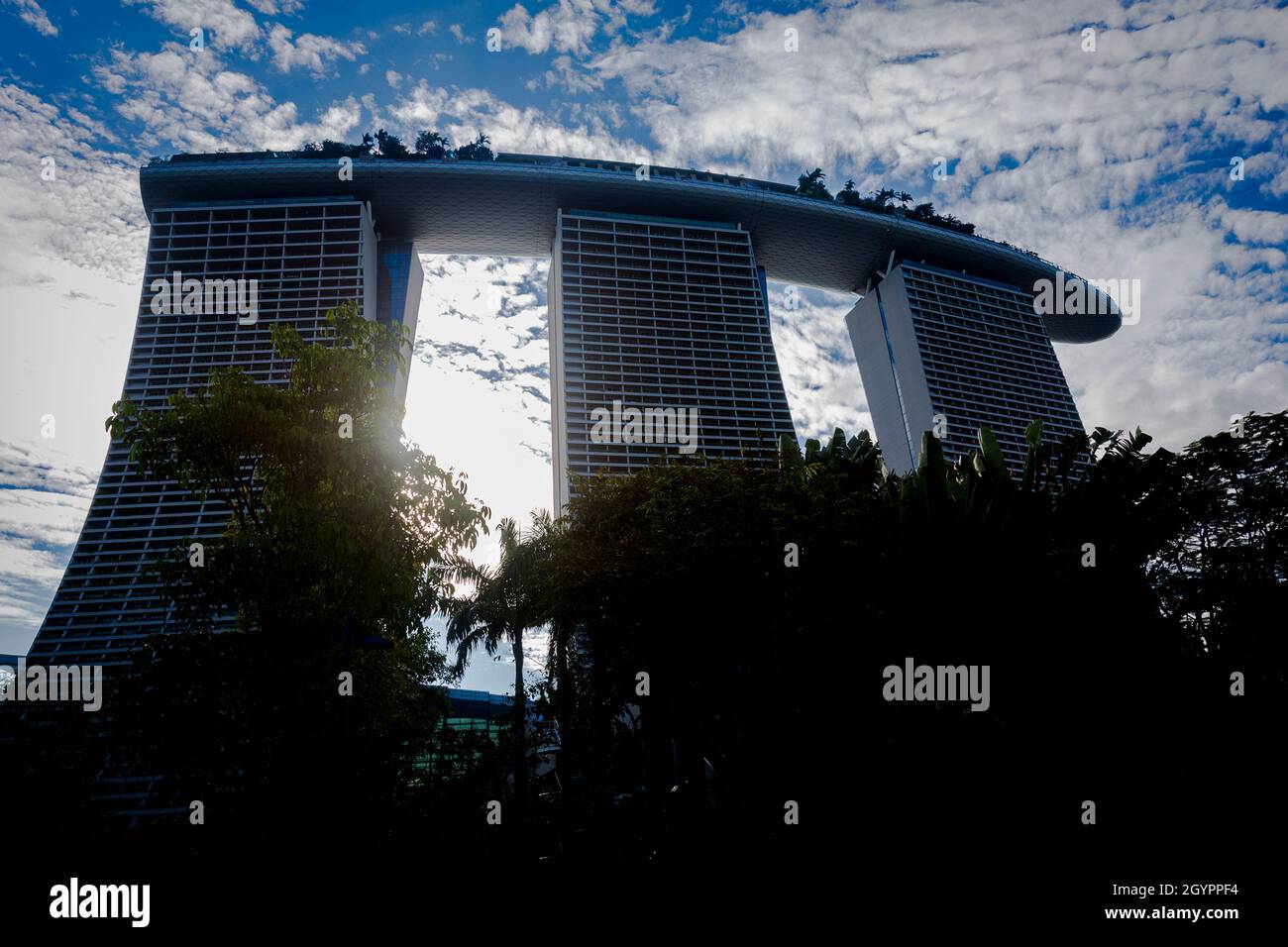 Il resort Marina Bay Sands si staglia su un cielo blu con il sole che passa attraverso il mezzo di due edifici. Foto Stock