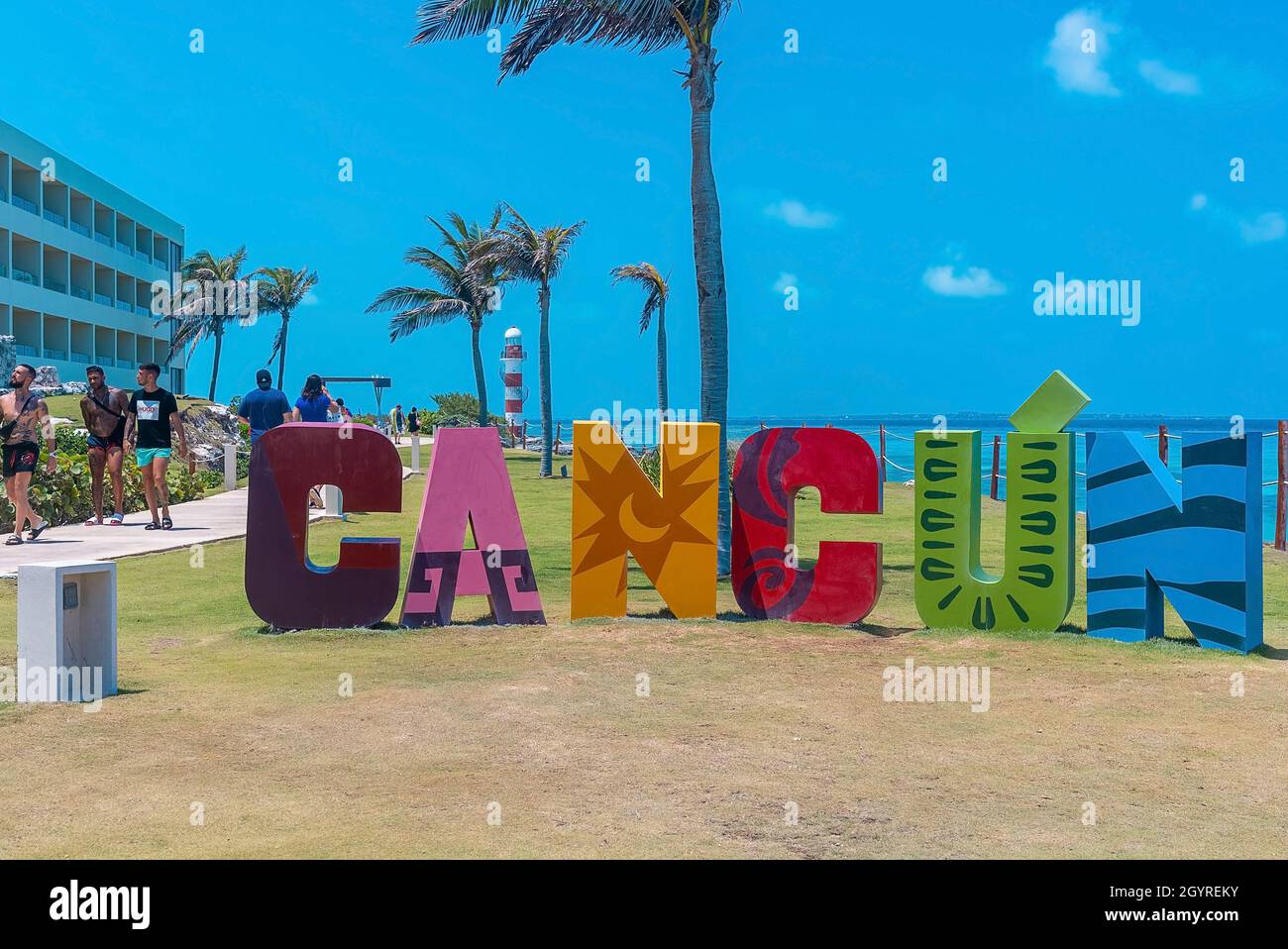 Cartello con il nome di Cancun al parco con turisti che camminano per mare Foto Stock