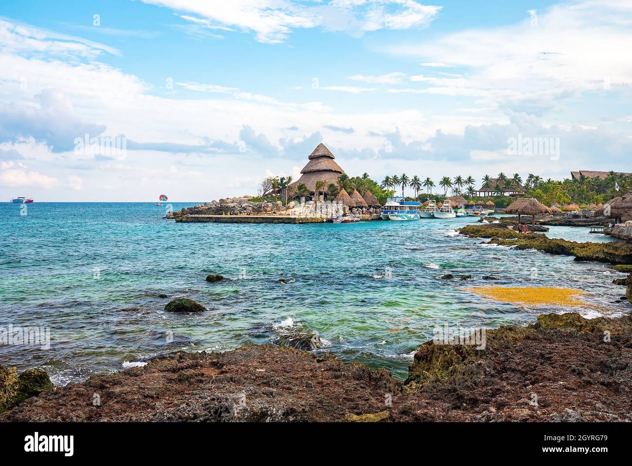 Resort ecologico con tetto di paglia e yacht ormeggiati al porto Foto Stock