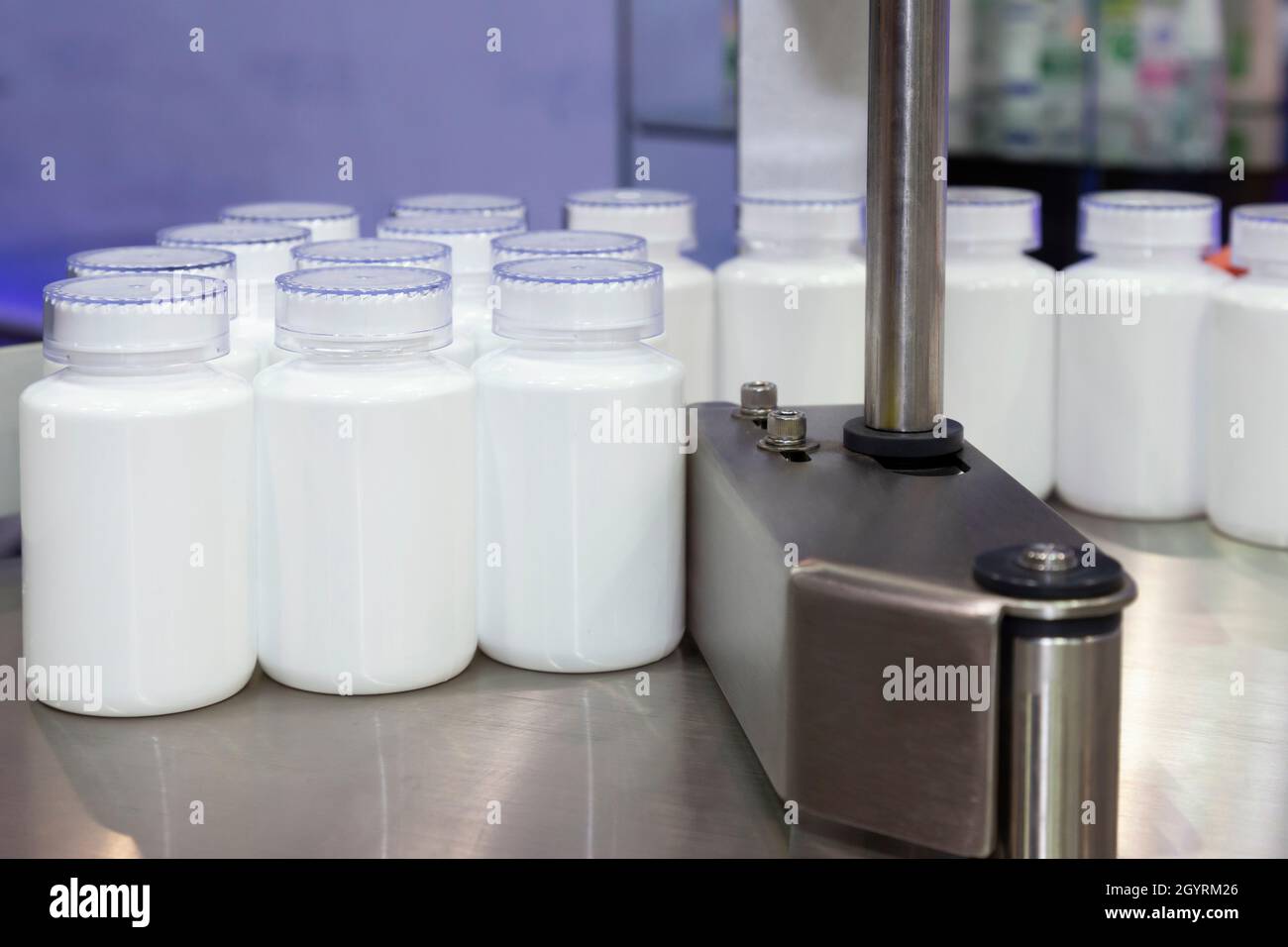 flacone di plastica bianca per medicina o cosmetici sulla linea di produzione del nastro trasportatore presso la macchina di riempimento nella produzione sanitaria. Foto Stock