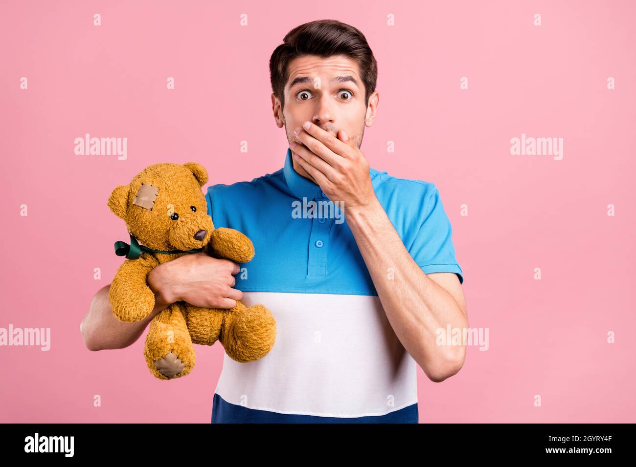 Foto di brunet triste millennial ragazzo tenere giocattolo indossare a strisce polo isolato su sfondo rosa Foto Stock