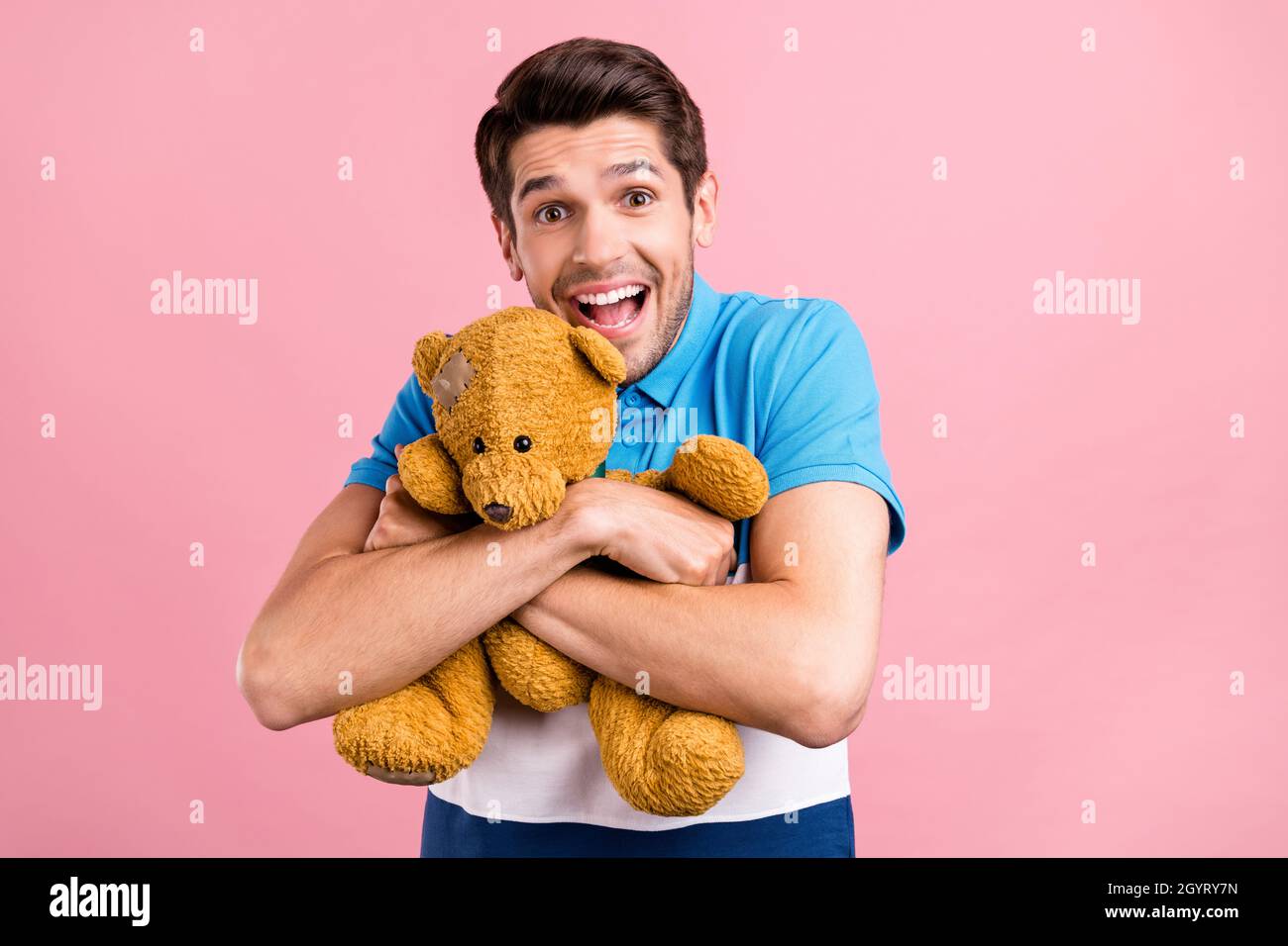 Foto di funky brunet millennial guy hug giocattolo indossare a strisce polo isolato su sfondo rosa Foto Stock