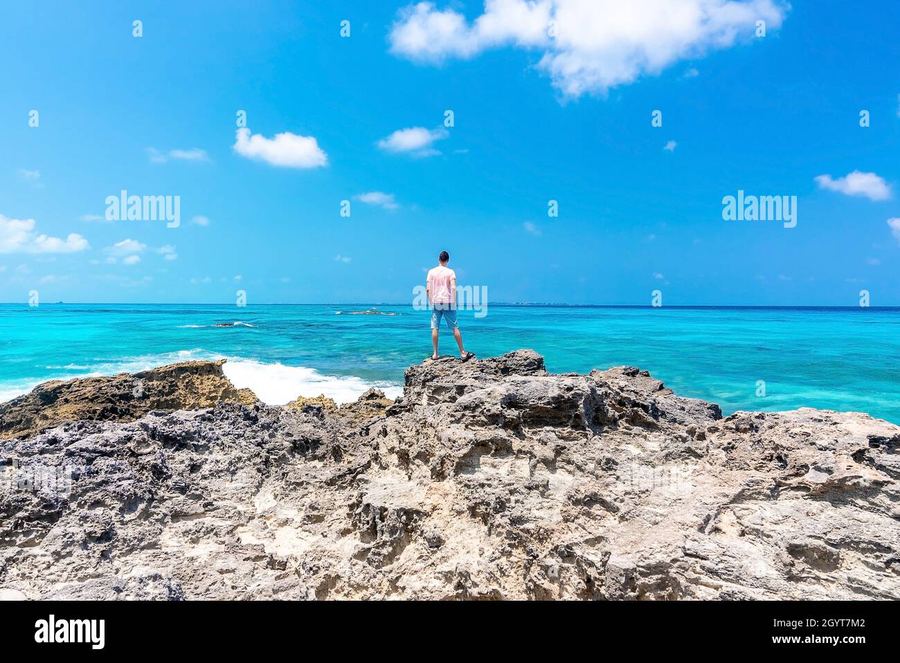 Vista posteriore dell'uomo in piedi di rocce e guardando il mare e il cielo Foto Stock