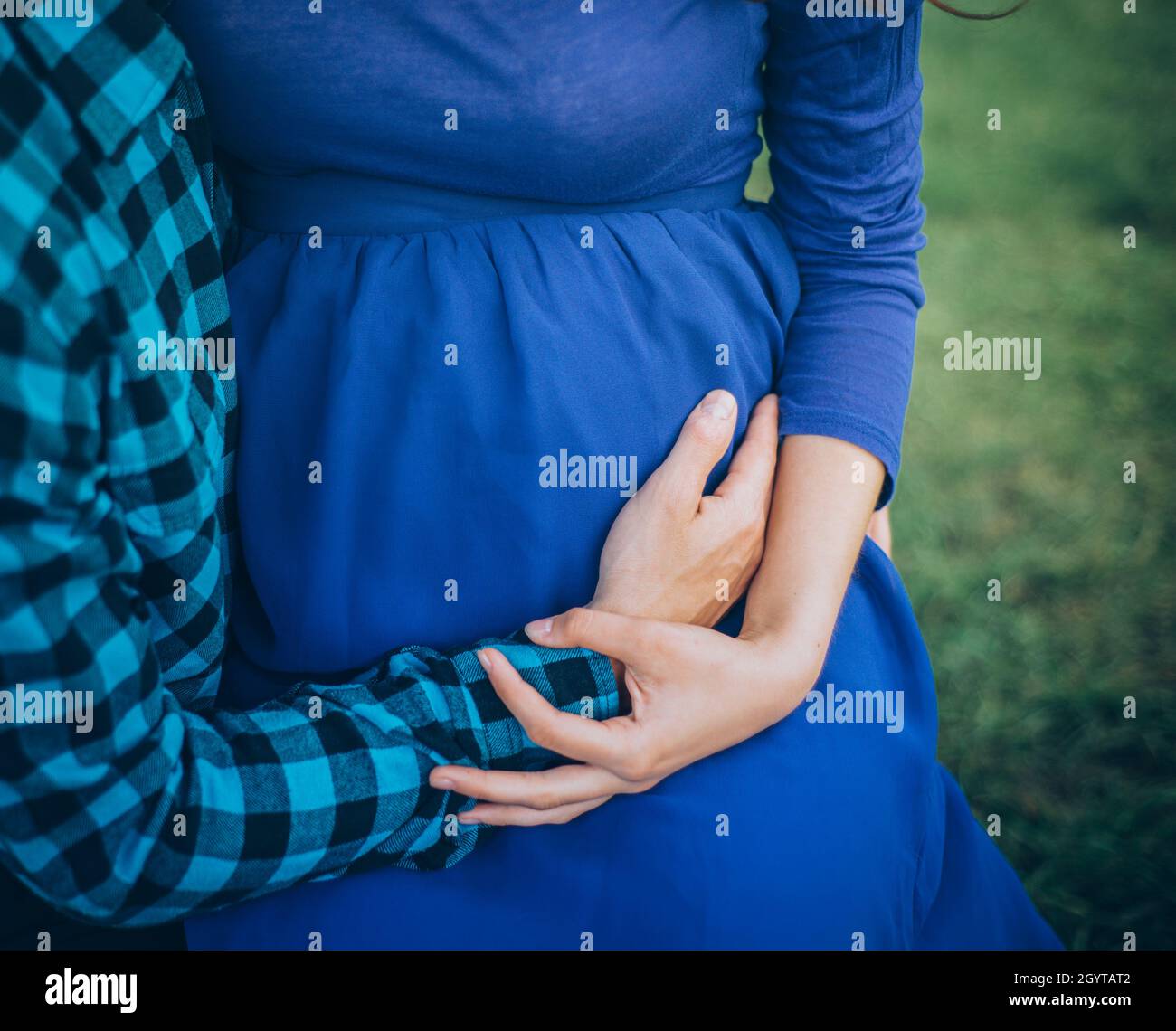 coppia incinta che tiene il ventre in abito blu e camicia Foto Stock
