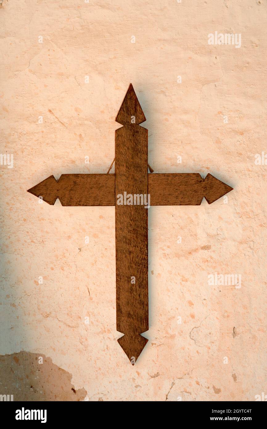 Un crocifisso in legno è appeso al muro di una storica casa in adobe al museo di storia vivente El Rancho de las Golondrinas vicino a Santa Fe, New Mexico. Foto Stock