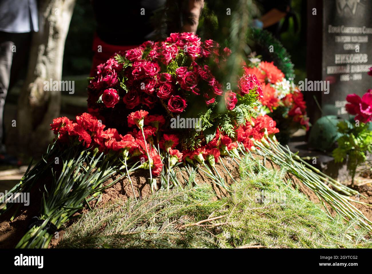 Fiori sulla tomba. Cerimonia funeraria. Fiori giacciono a terra. Tomba piena. Foto Stock