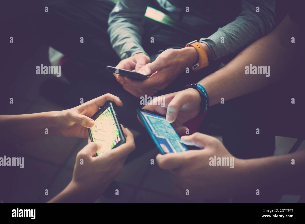 Primo piano delle mani di tre giovani amici dipendenti dalla tecnologia che giocano insieme con gli smartphone. Ragazzi adolescenti che usano i telefoni cellulari per la rete sociale Foto Stock