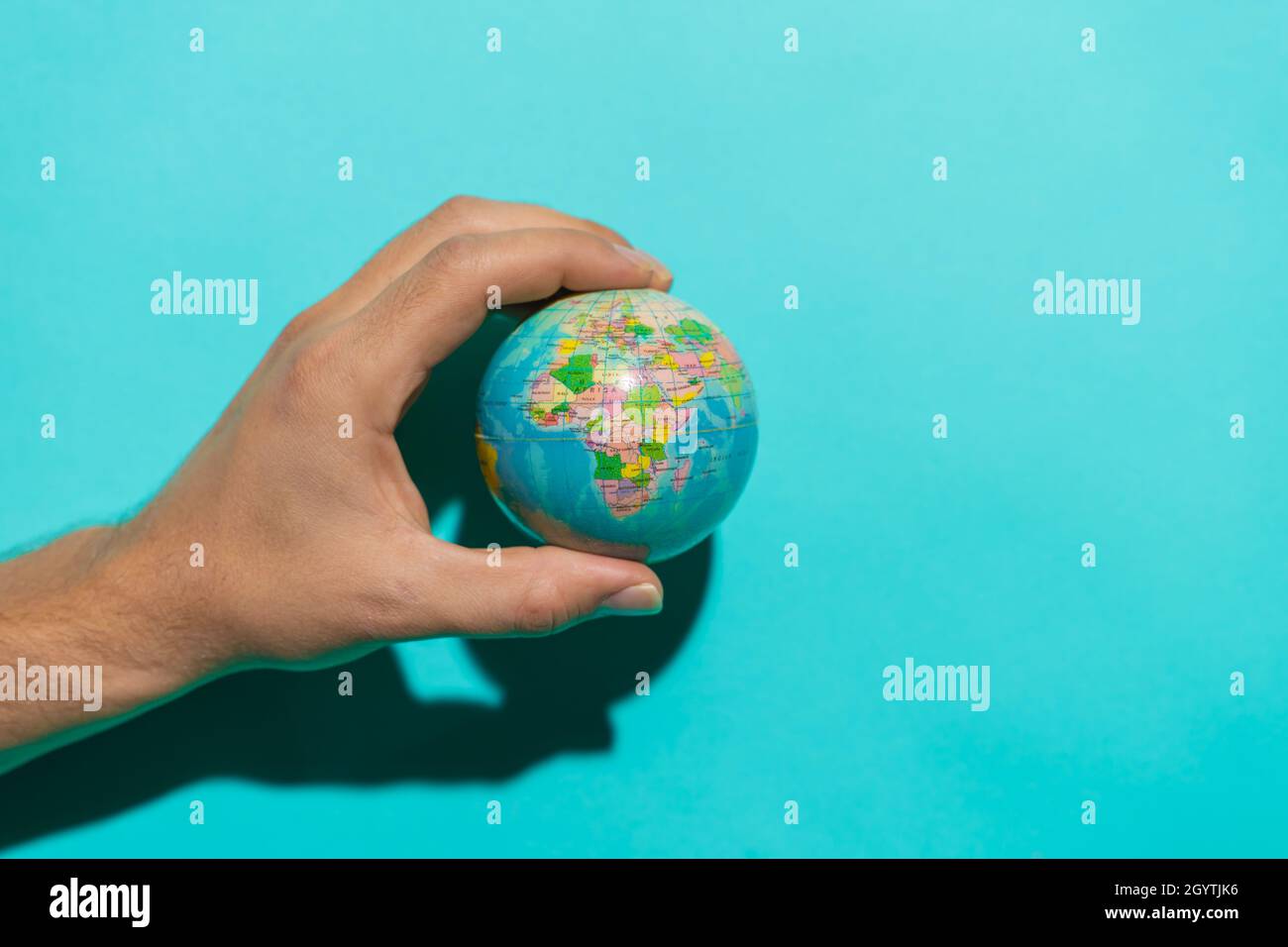Sfera a globo in mano con sfondo blu colorato e spazio di copia per il testo. Foto Stock