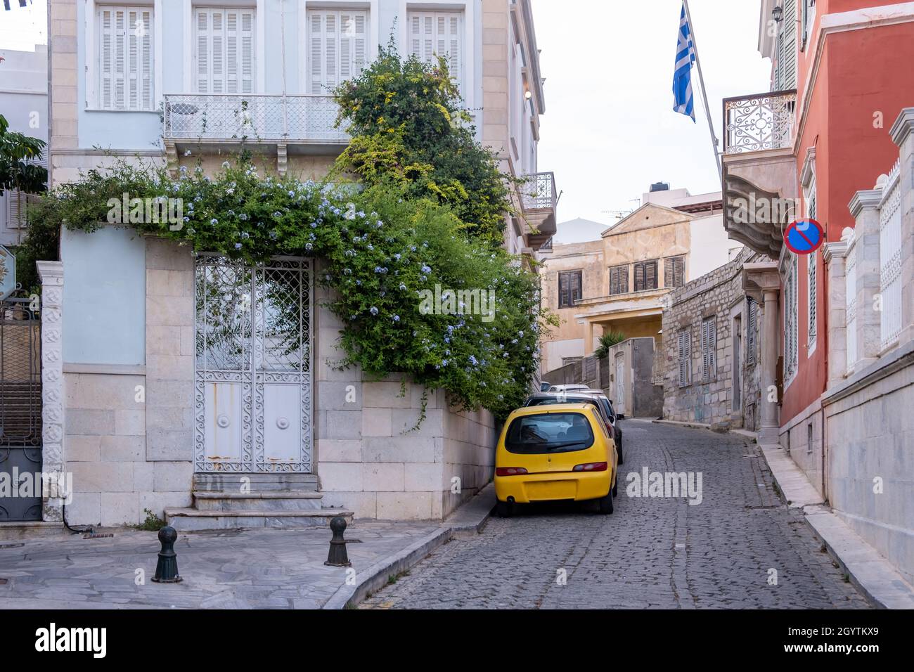 Edifici tradizionali in pietra e marmo a Ermoupoli città isola di Syros destinazione Cicladi Grecia. Esterno cancello in metallo con ringhiere viola fiore Foto Stock
