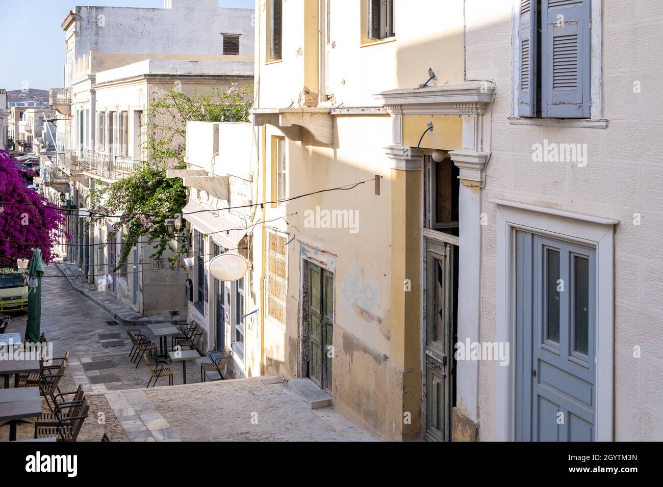 Cafe bar esterno tra edifici tradizionali su strada acciottolata Ermoupolis città capitale dell'isola di Syros Cicladi destinazione giorno d'estate Grecia. Foto Stock