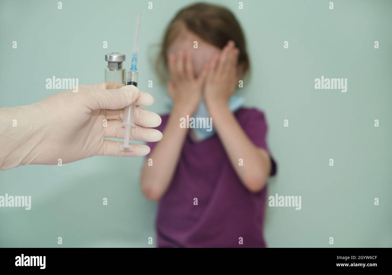 il bambino gli coprì il volto con le mani come segno contro il vaccino, gli coprì il volto con paura, anticavinazione Foto Stock