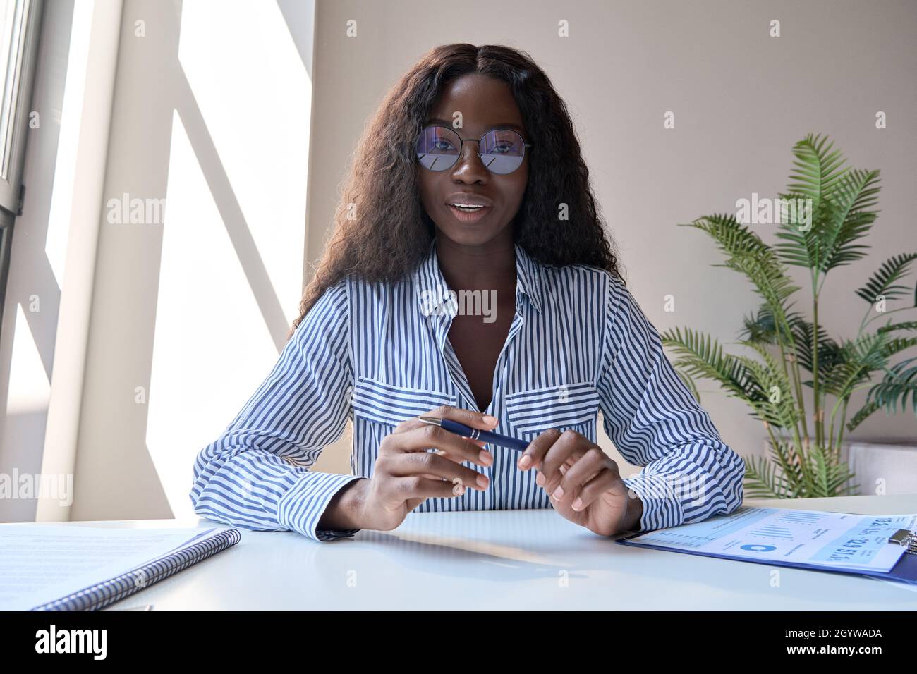 Black woman manager che ha incontri virtuali con diversi uomini d'affari. Foto Stock