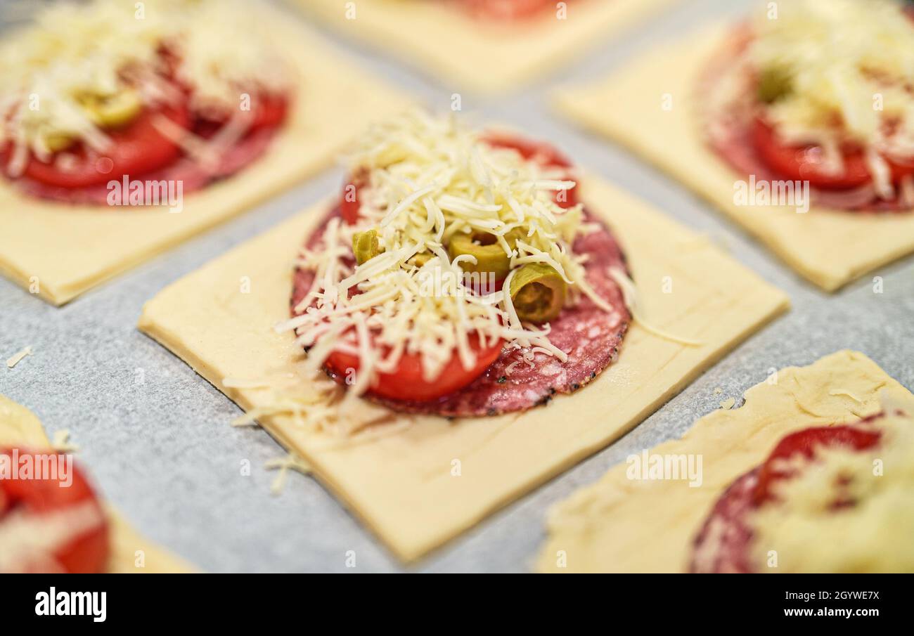 Mini pizze quadrate con salame, formaggio, olive e pomodoro. Foto Stock