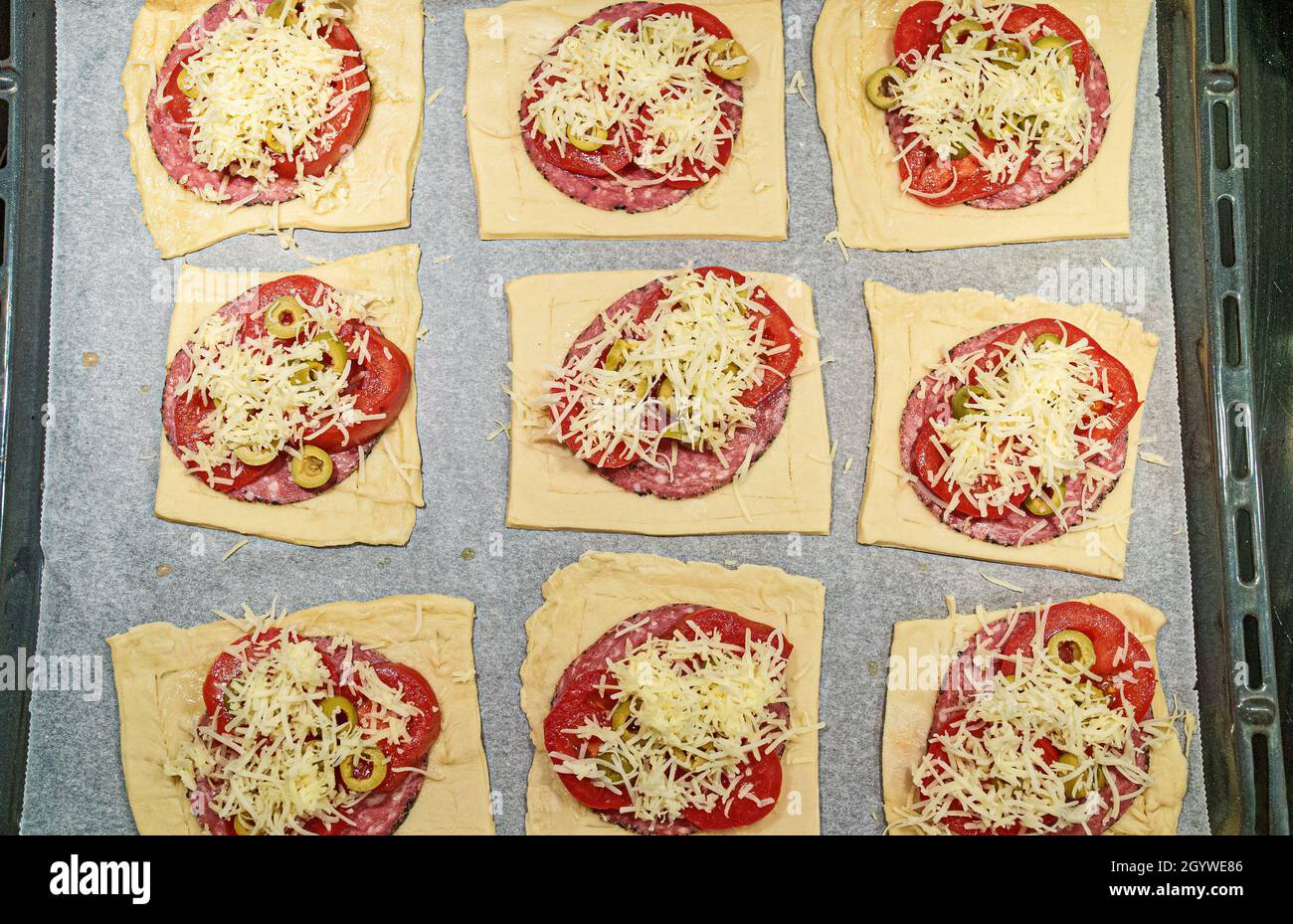 Mini pizze quadrate con salame, formaggio, olive e pomodoro. Foto Stock