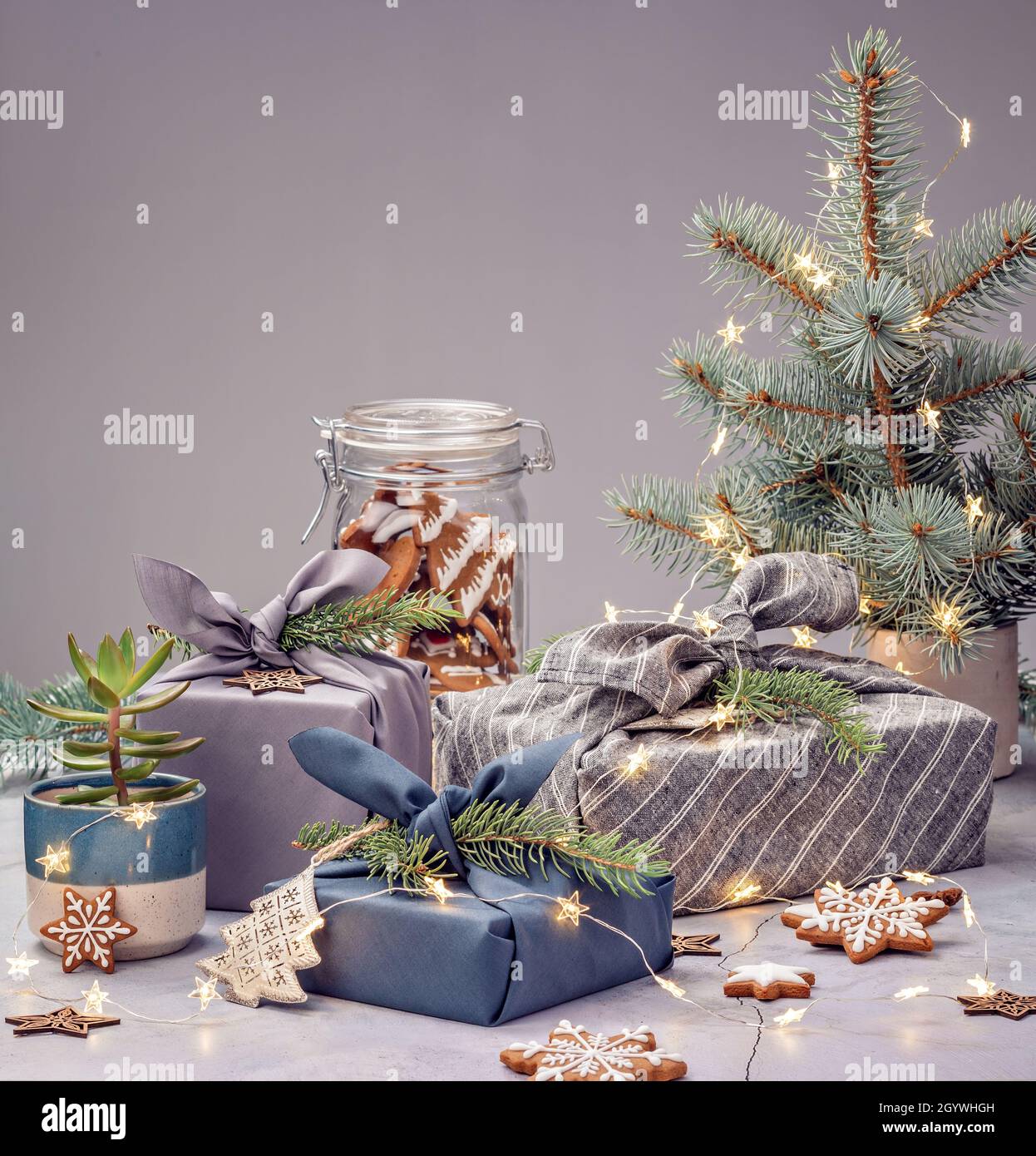 Zero rifiuti di Natale riciclaggio, riutilizzo, stile di vita sostenibile concetto. Confezione regalo ecologica in stile furoshiki, piante e biscotti fatti in casa. Foto Stock