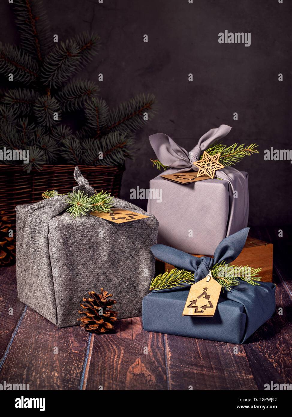 Tre scatole regalo ecologico in stile furoshiki su sfondo scuro. Zero rifiuti di Natale riciclaggio, riutilizzo, stile di vita sostenibile concetto. Foto Stock