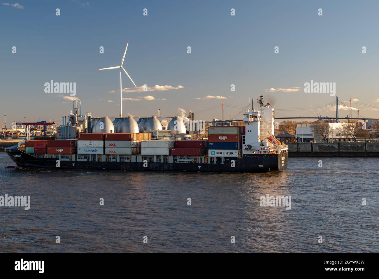 Amburgo, Germania-05.03.2021:piccolo container freighter sul fiume elba e sullo sfondo una turbina eolica e il ponte köhlbrand Foto Stock