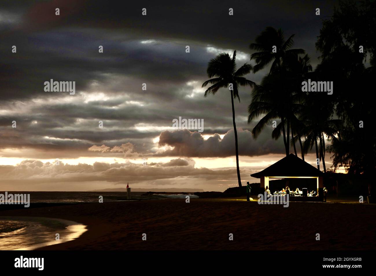 Riunione di famiglia dopo il tramonto alla spiaggia di Saltstagno a Kauai Foto Stock