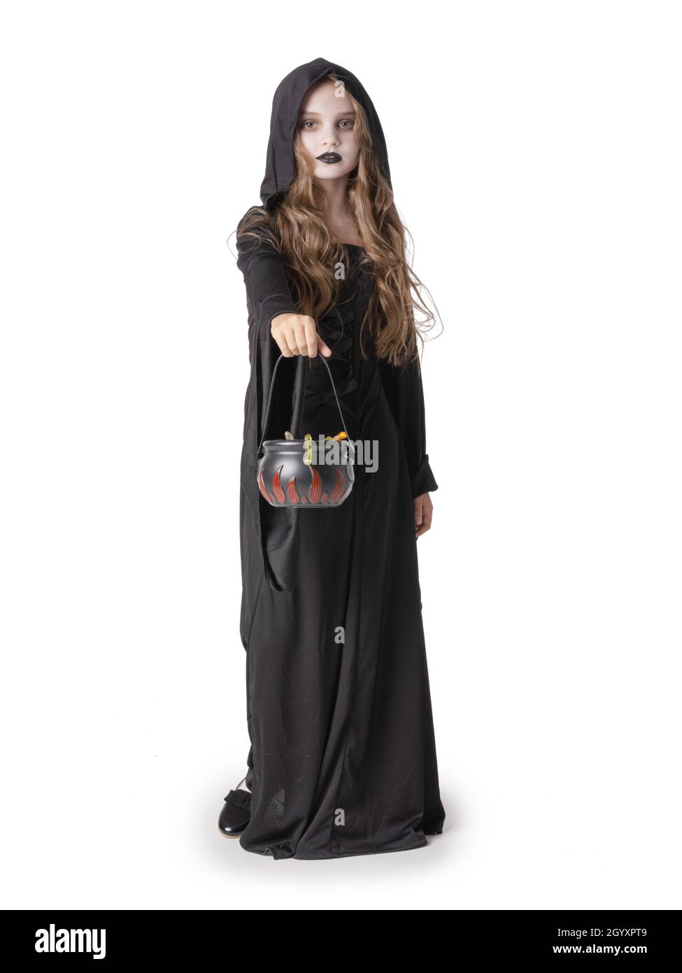 Ritratto di bambina in vestiario nero con cauldron cestino di dolci vermi isolato su sfondo bianco, Halloween costume strega, tempo di festa, Foto Stock