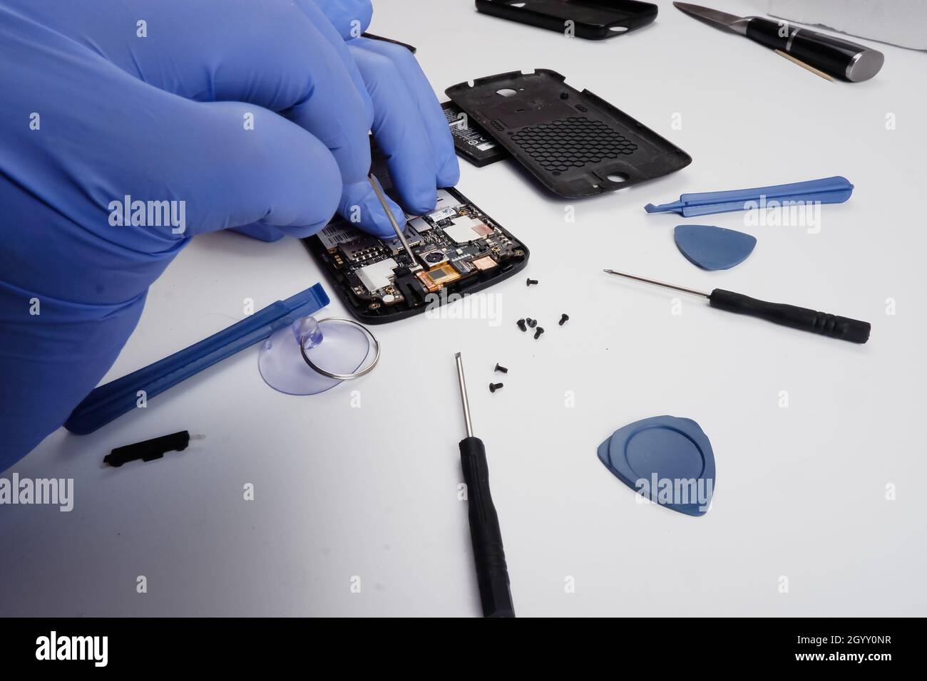 il master ripara uno smartphone rotto con l'aiuto di strumenti. Foto Stock