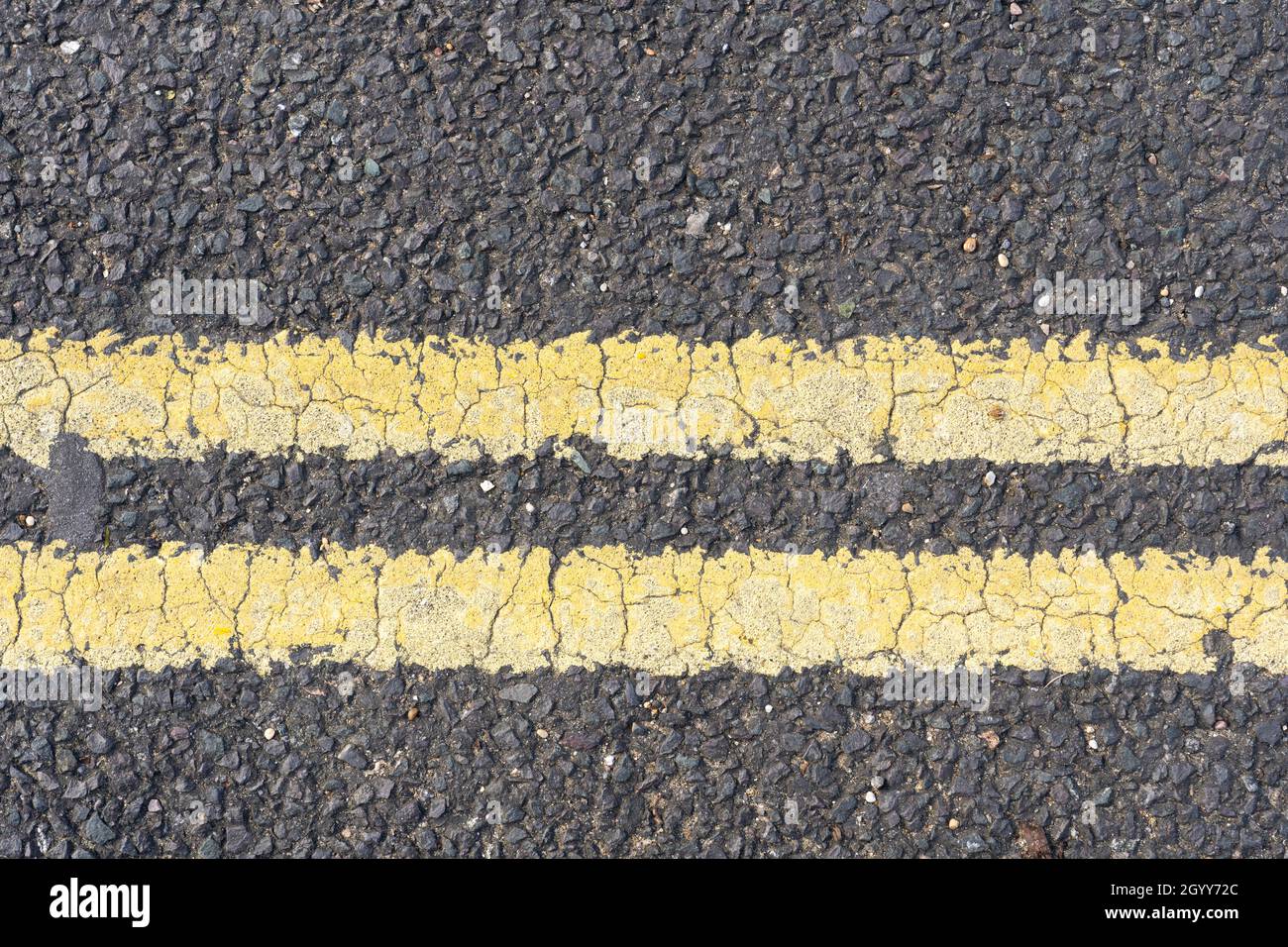 Doppie linee gialle in vernice termoplastica su una strada asfaltata in Inghilterra che proibiscono il parcheggio e l'attesa in qualsiasi momento Foto Stock