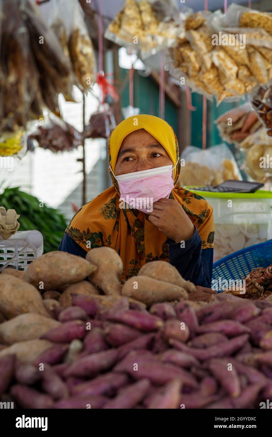 Kuala Lumpur, Malesia - 18 settembre 2021 Donna venditore che indossa maschera facciale presso il locale ingredienti alimentari freschi stalla. Foto Stock