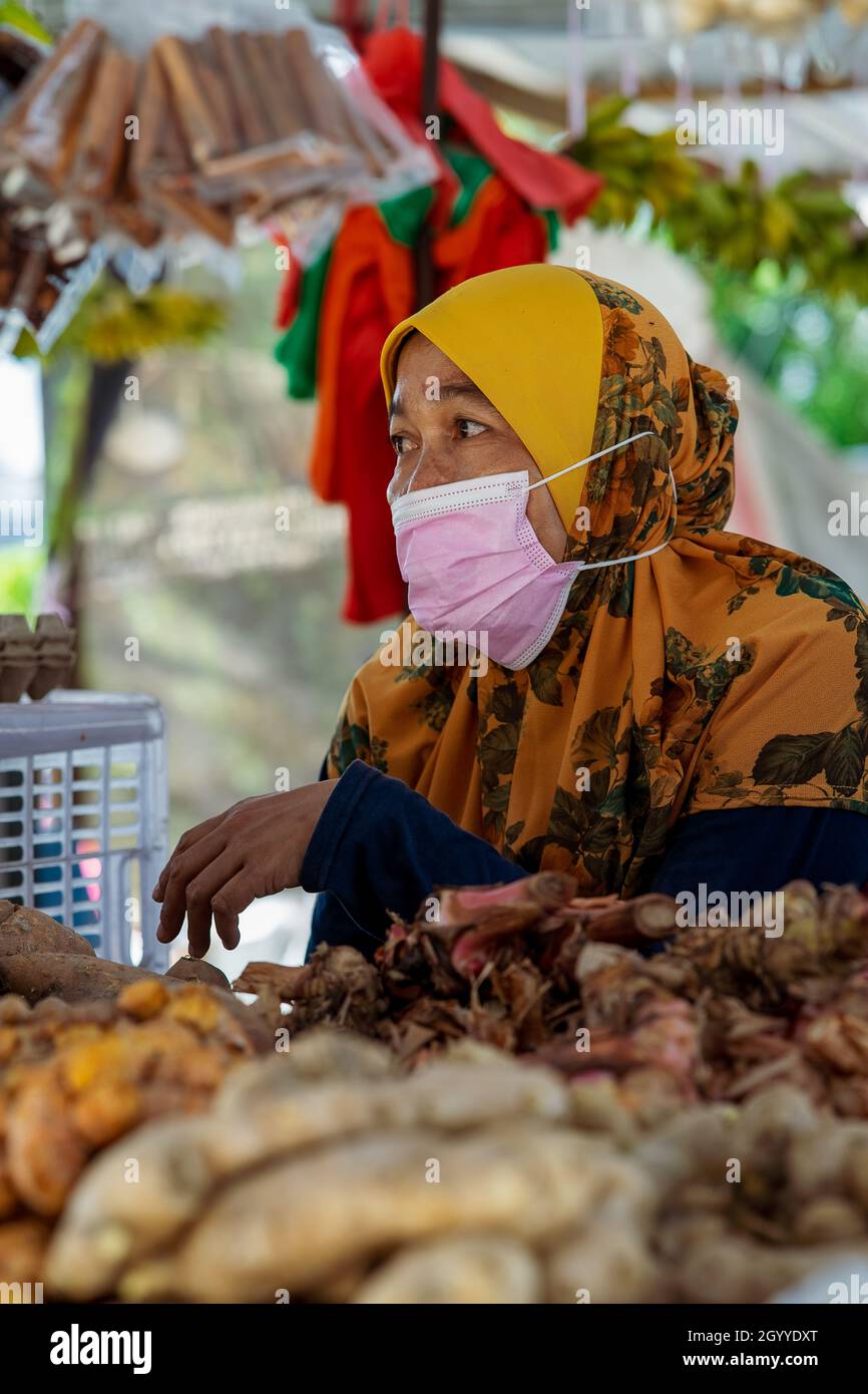Kuala Lumpur, Malesia - 18 settembre 2021 Donna venditore che indossa maschera facciale presso il locale ingredienti alimentari freschi stalla. Foto Stock