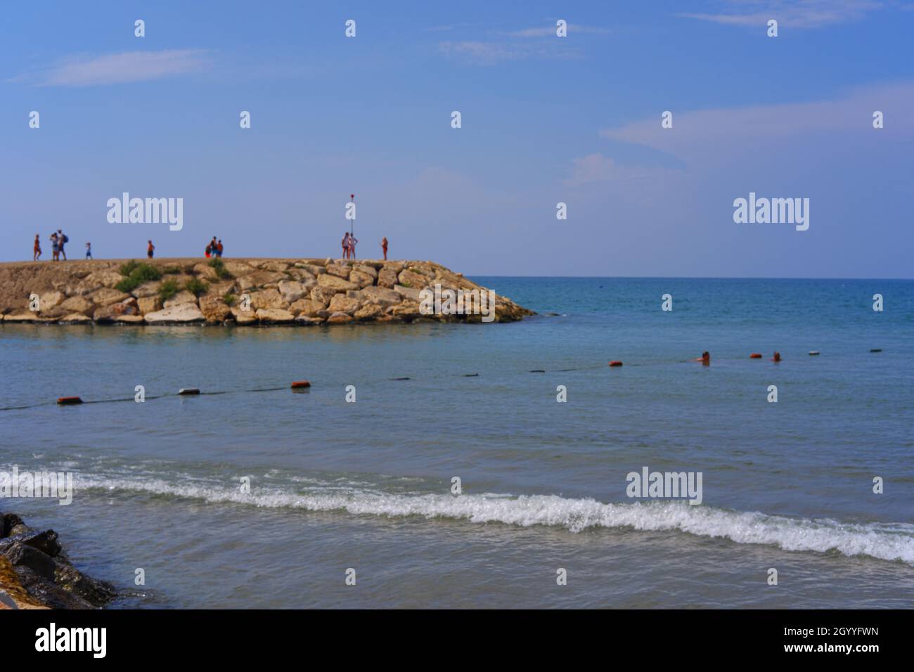 Rocce di un piccolo porto e persone che si levano in piedi su di esso in una giornata estiva soleggiato in Turchia di Antalya Foto Stock