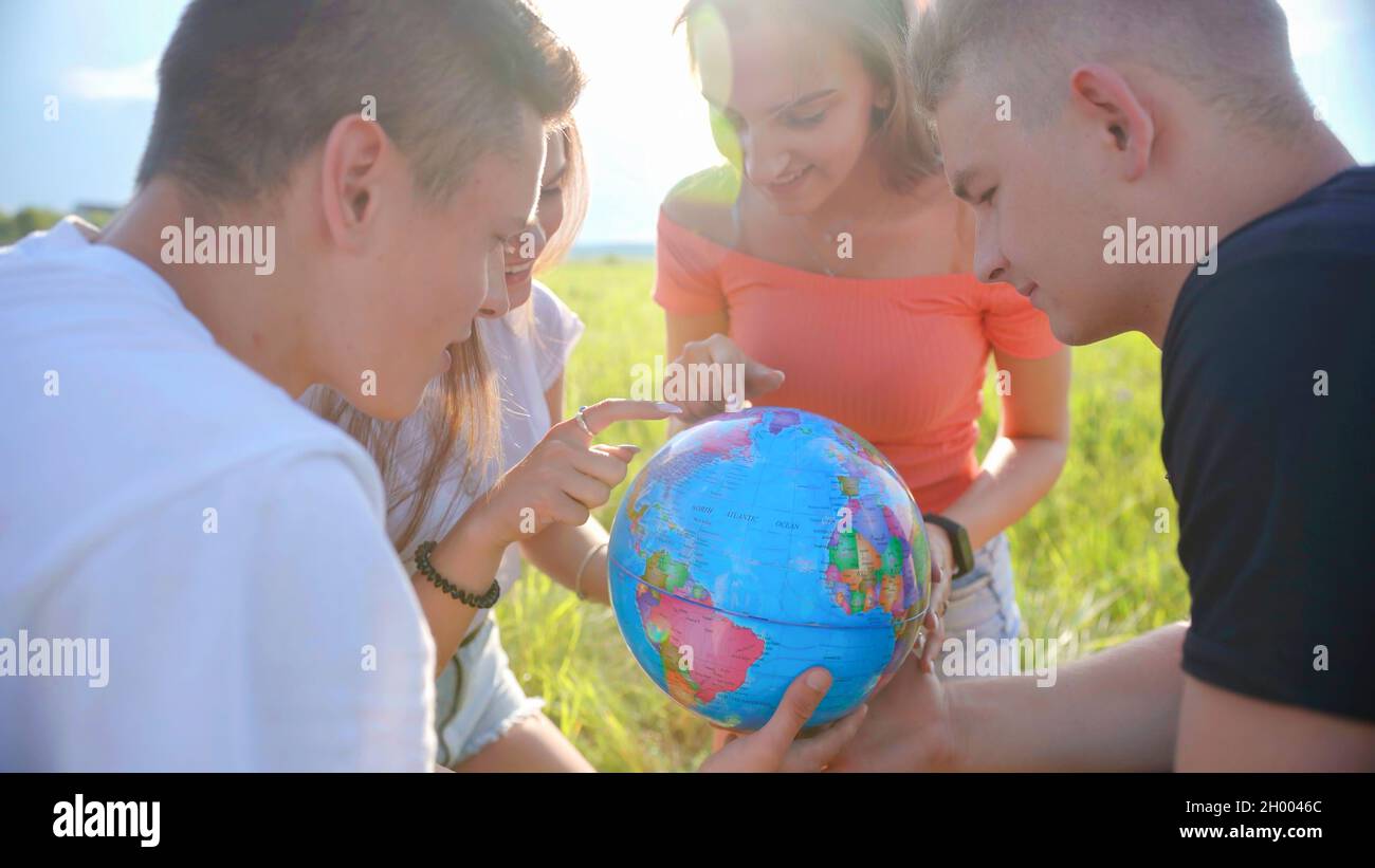 Gli amici stanno esaminando il globo della terra. Foto Stock