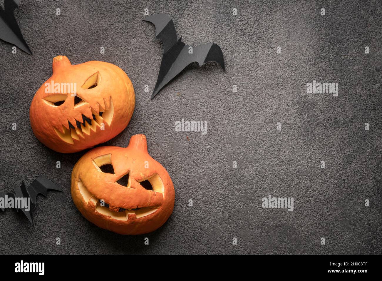 halloween zucca flatlay, copia foto spazio su sfondo scuro modello. Due paurose zucche autunnali con la testa di Jack, un mockup con un minaccioso grin e. Foto Stock